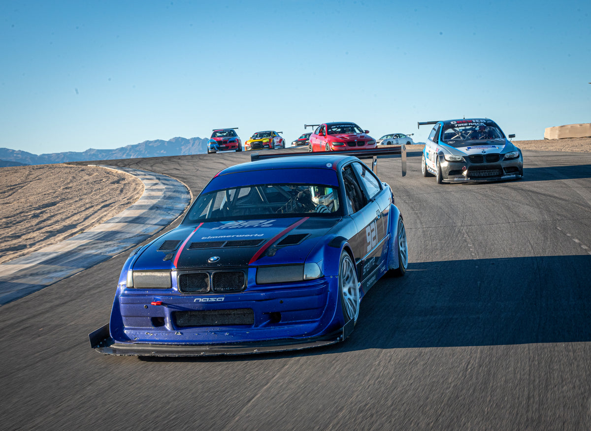 Blue BMW E36 race car leading a group on track