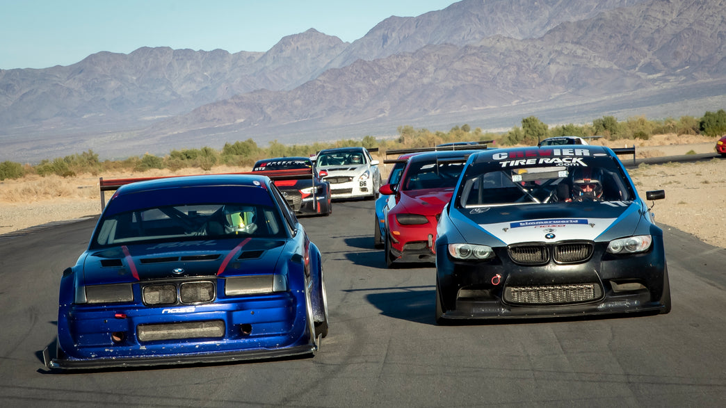 Blue BMW E36 race car leading a BMW M3 on track