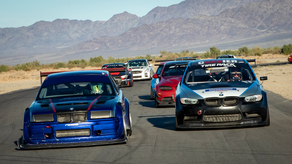 Blue BMW E36 race car leading a BMW M3 on track