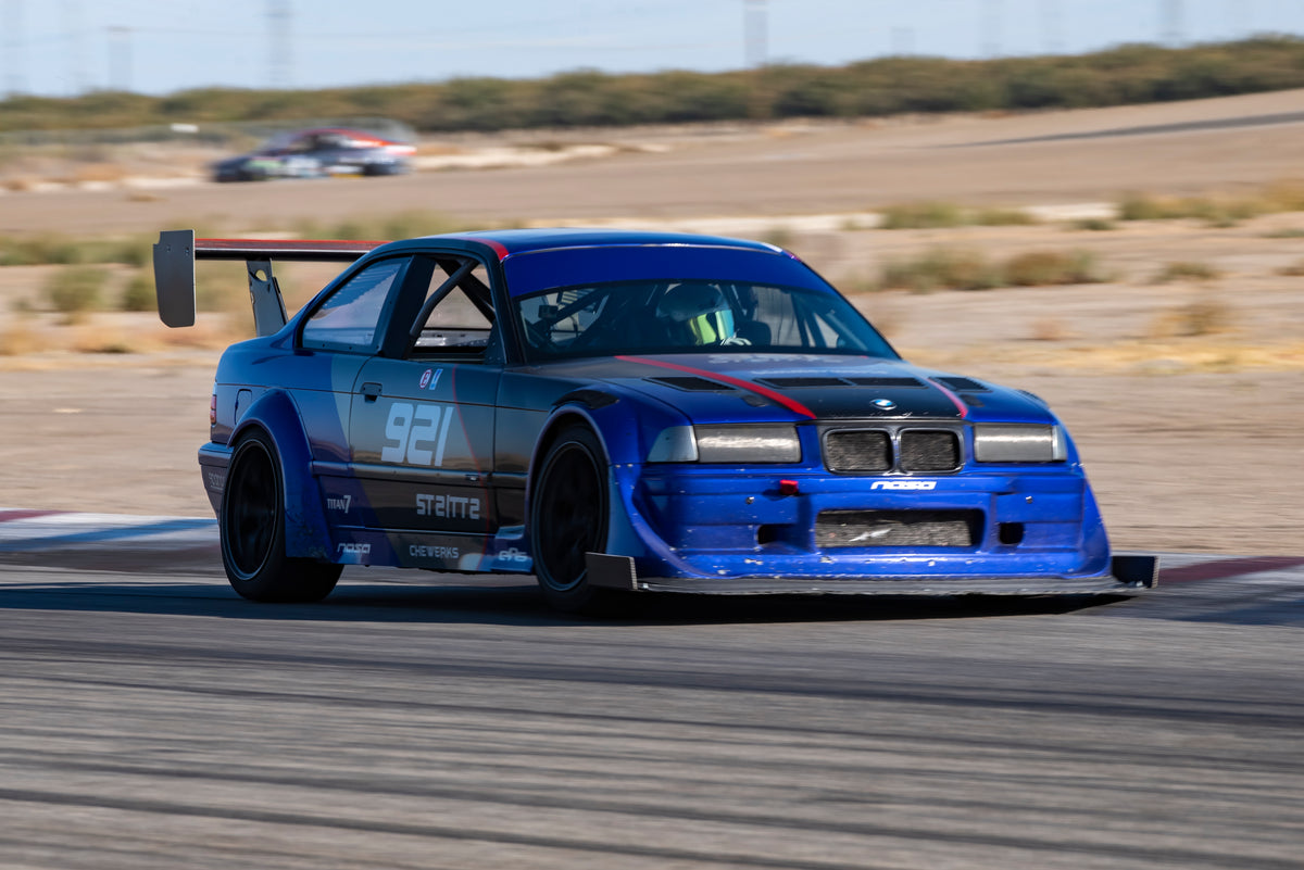 Blue BMW E36 race car with rear wing on track